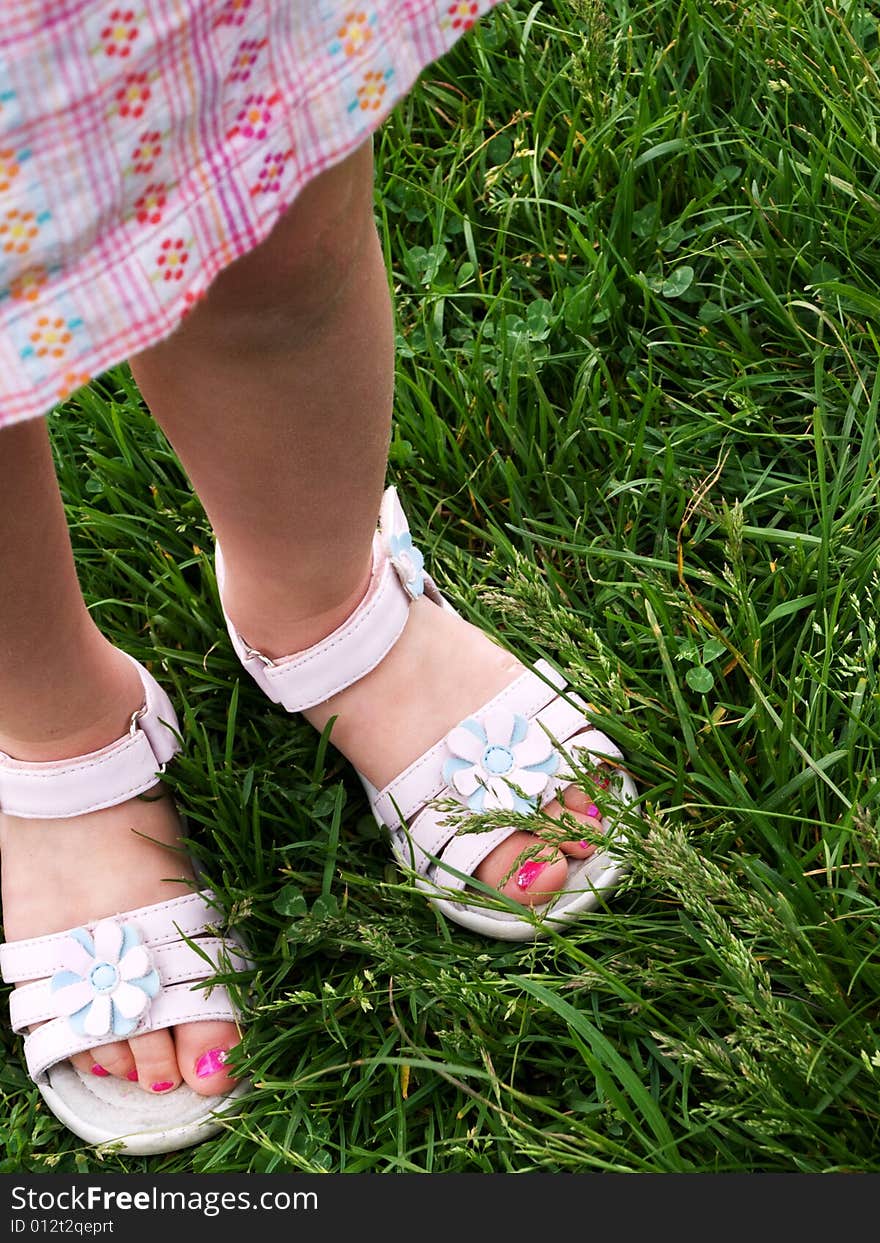 3 year old girl’s feet, standing in the grass, in white dress sandals, with bright pink salon-pedicured toenails. 3 year old girl’s feet, standing in the grass, in white dress sandals, with bright pink salon-pedicured toenails