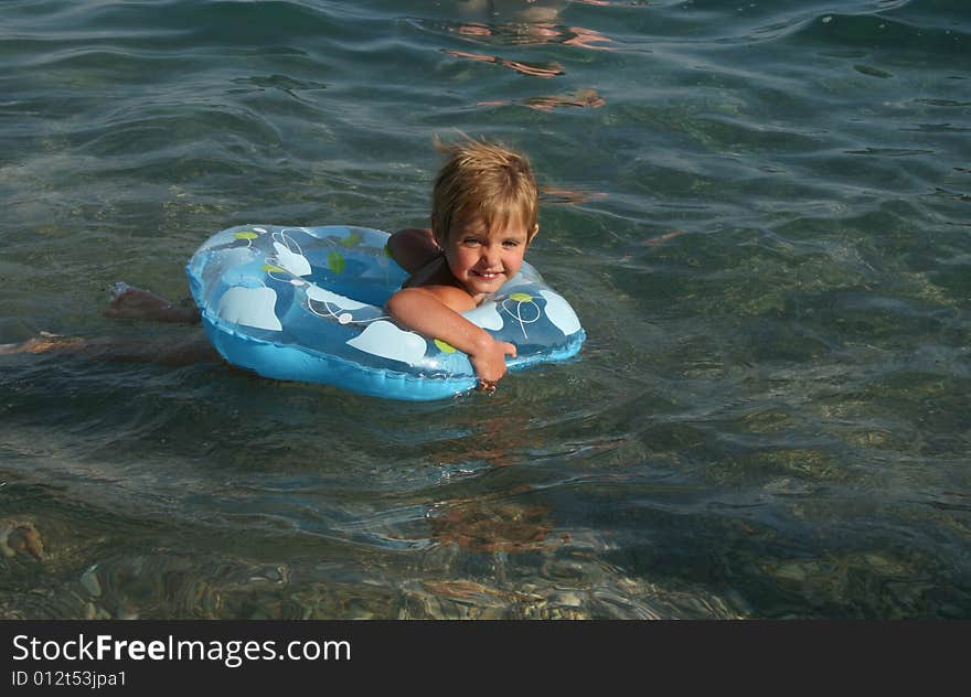 The little girl floats on a lifebuoy ring in the sea