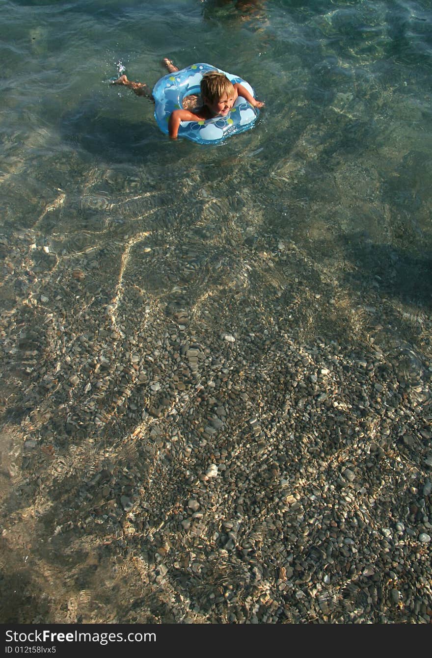 The little girl floats on a lifebuoy ring in the sea