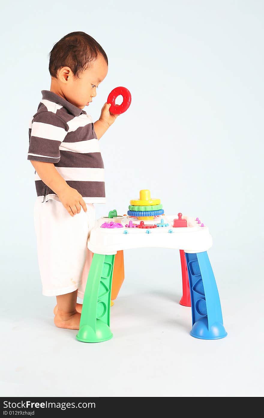 An unhappy asian toddler playing with his toy alone. An unhappy asian toddler playing with his toy alone