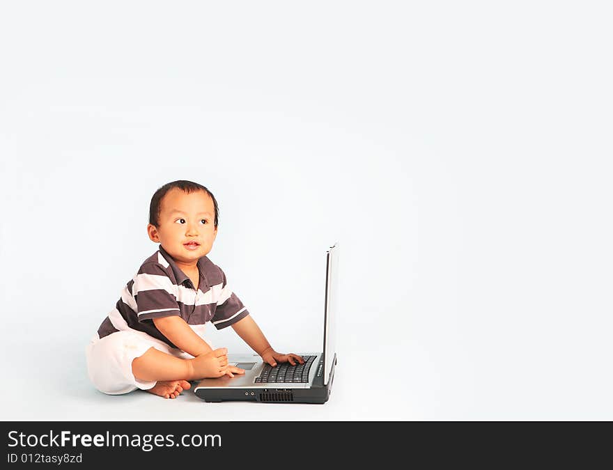 A happy toddler using a laptop computer. Eyes are looking up