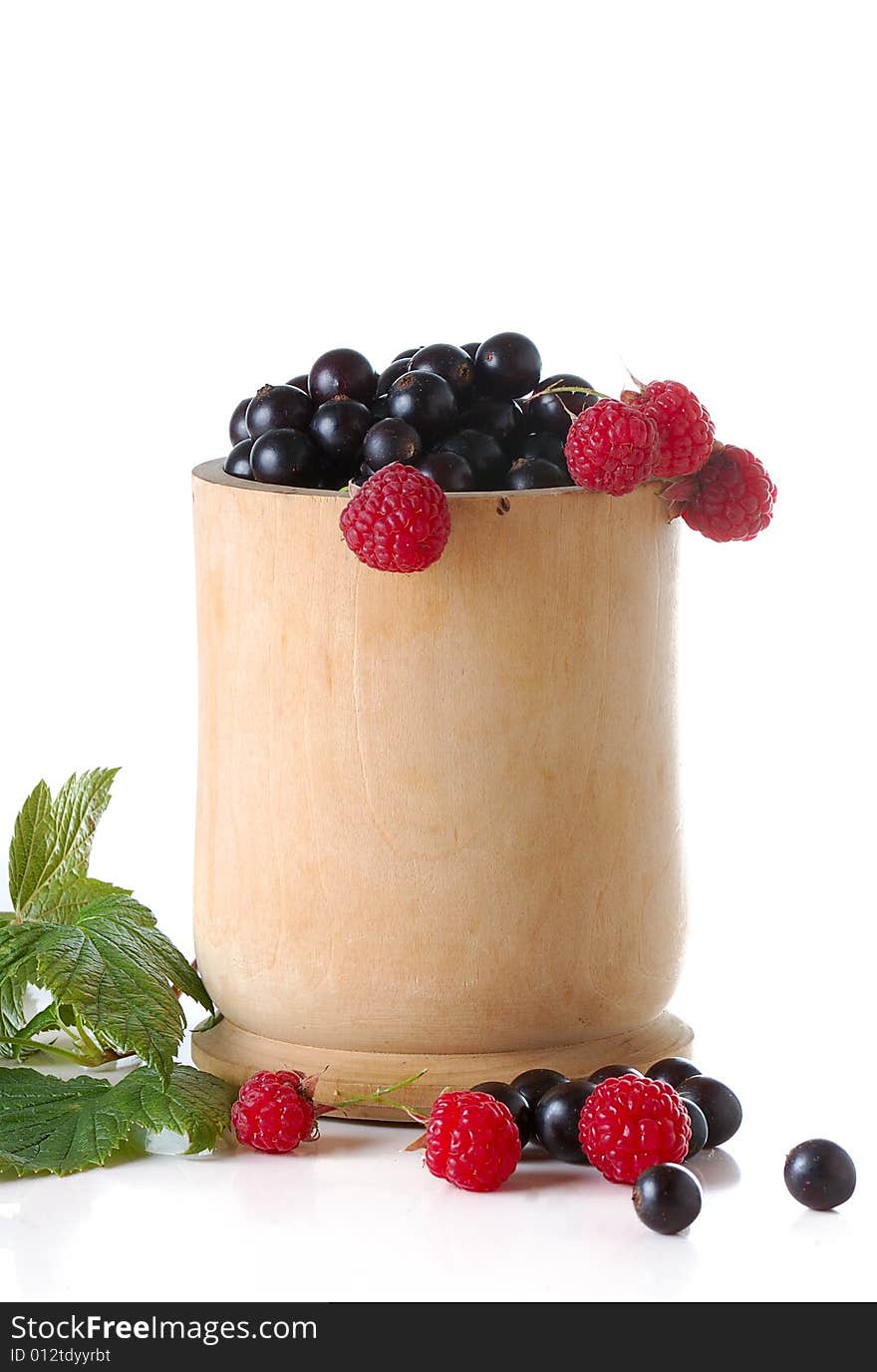 Black currant and raspberries in wood cup isolated on white