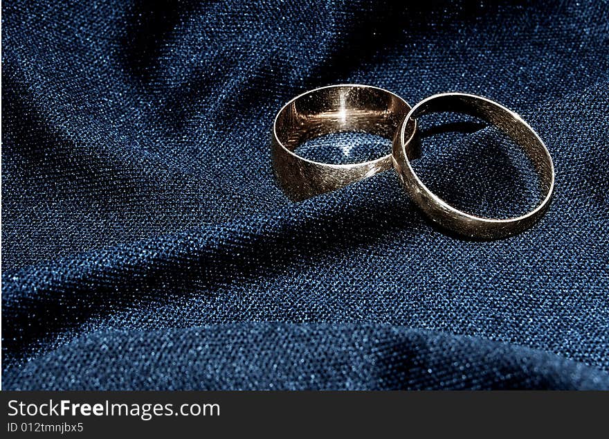 Two brilliant wedding rings on a black fabric.