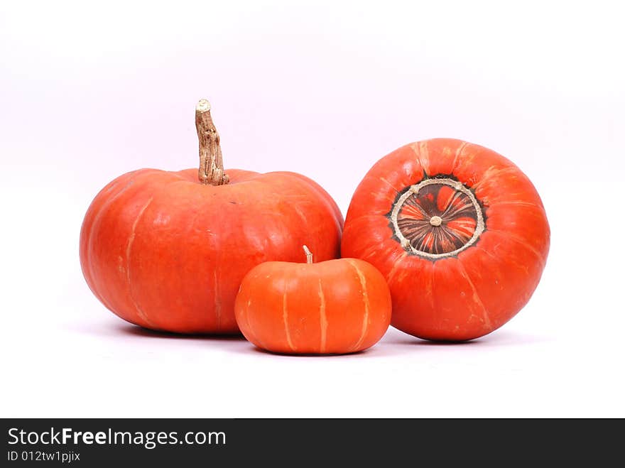 Three red pumpkins on white background.