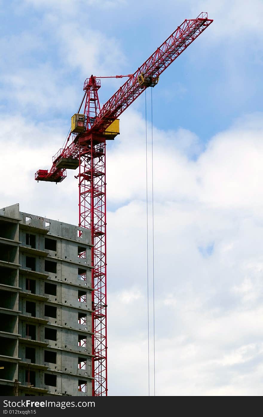 Building crane aganist cloudy sky and building und