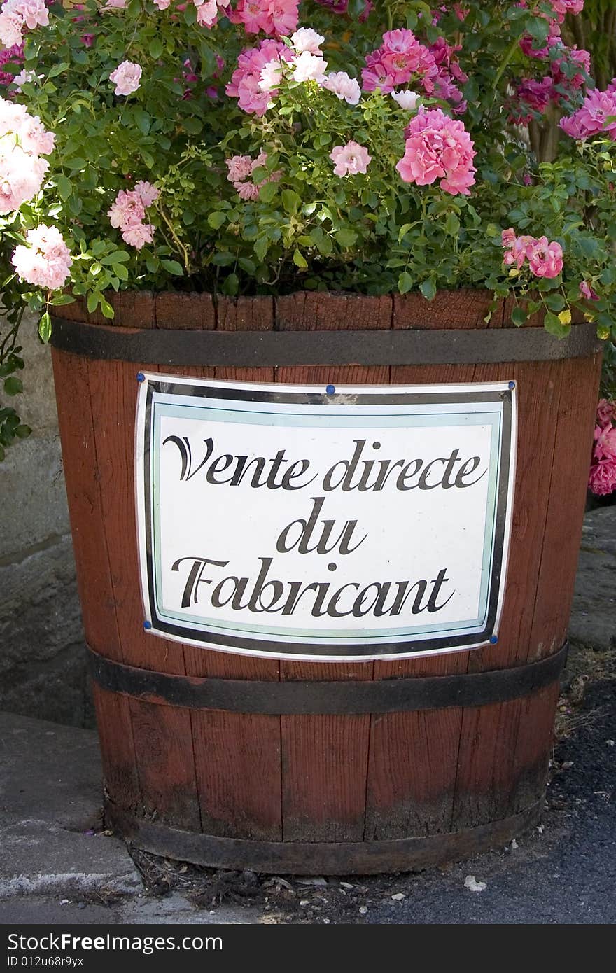 Large barrel filled with pink flowers with the words 'vente directe du fabricant' (direct sales) written on the side