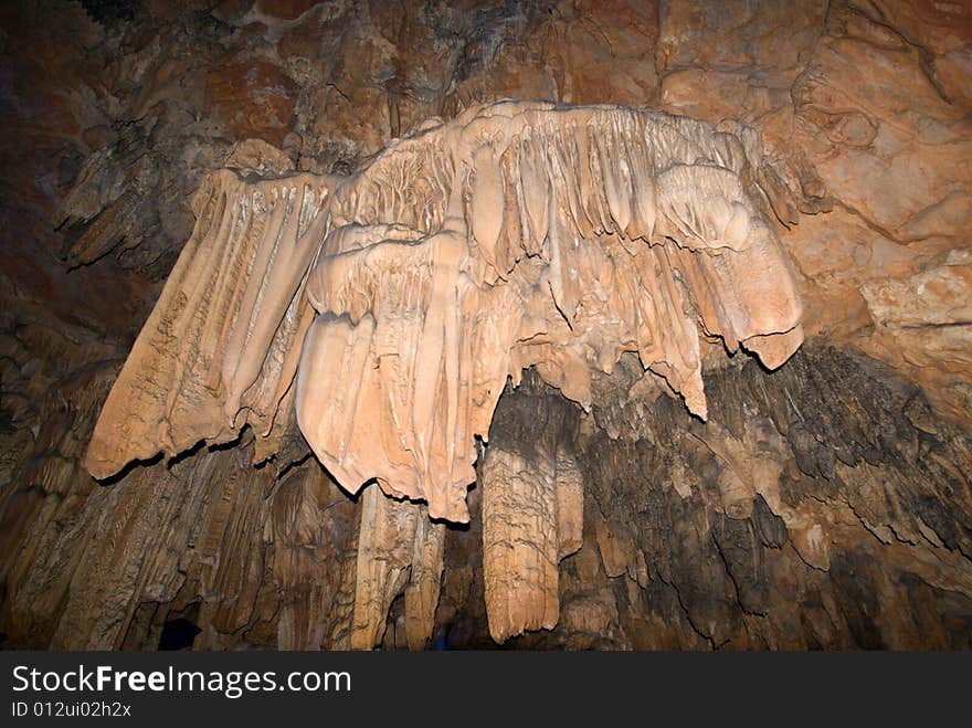 Water-eroded Reed Flute Cave with its stalactites, stone pillars and rock formations created by carbonate deposition, illuminated by colored lighting. Guilin, China