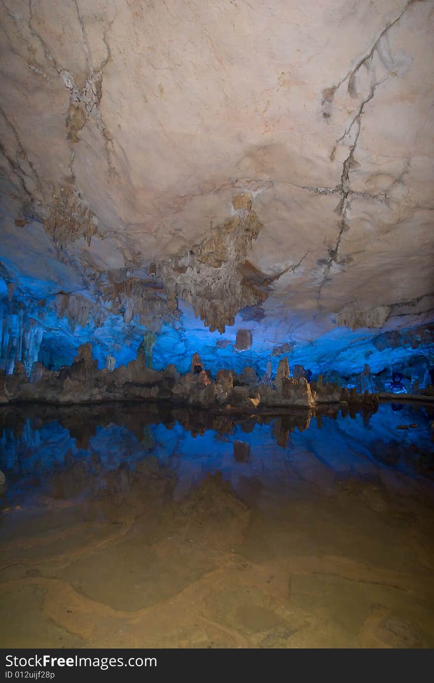 Water-eroded Reed Flute Cave with its stalactites, stone pillars and rock formations created by carbonate deposition, illuminated by colored lighting. Guilin, China