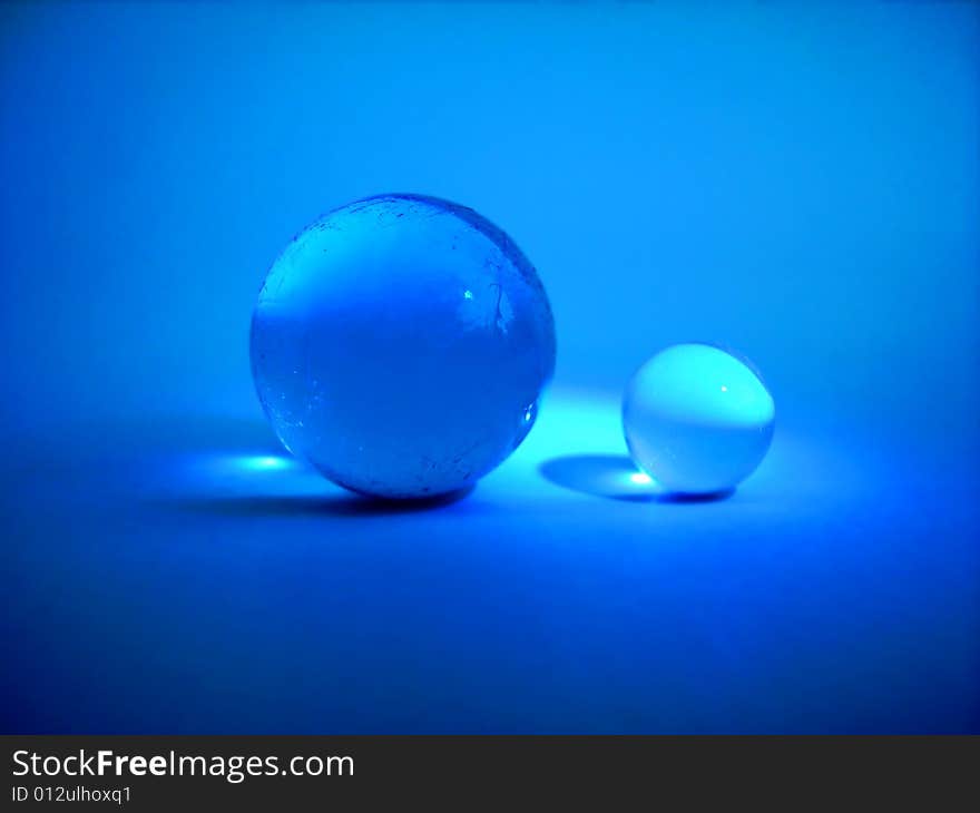 Two blue glass balls on blue background