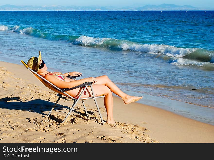 Young beautiful woman has a rest on coast of ocean