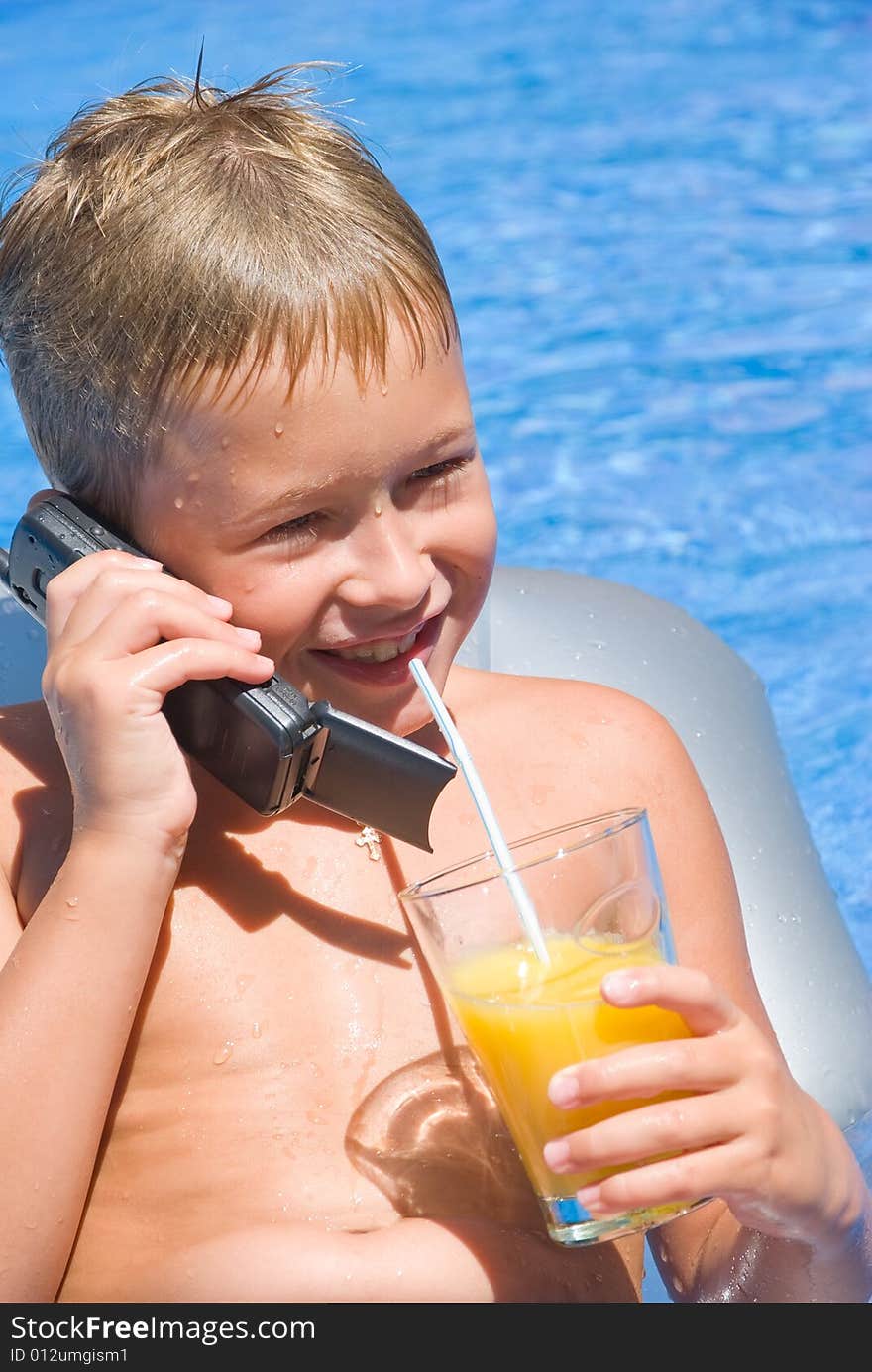 Boy speaks by phone and drinks orange juice