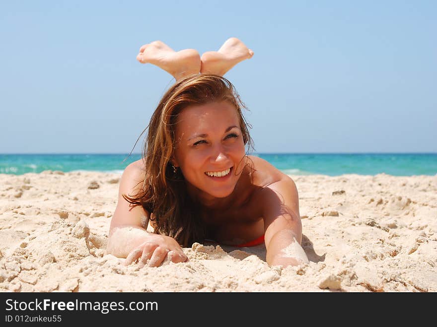 Young beautiful woman has a rest on coast of ocean. Young beautiful woman has a rest on coast of ocean