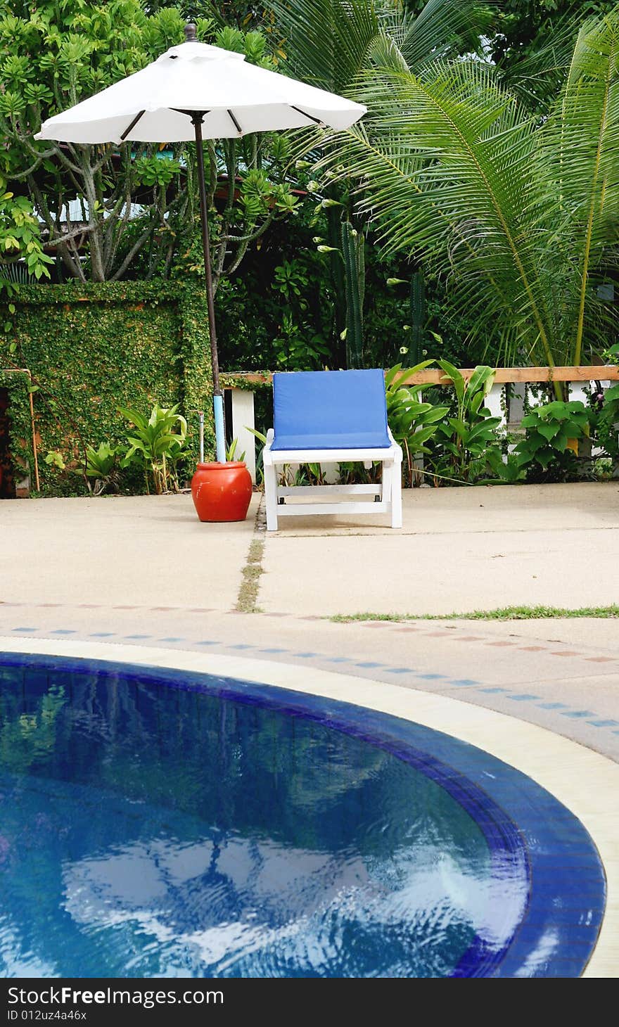 Deck chairs and umbrellas next to a swimming pool.