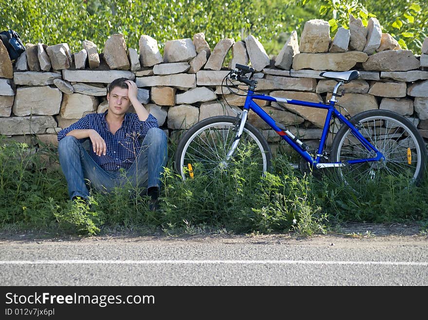 A young man with a bicycle in the green grass. A young man with a bicycle in the green grass