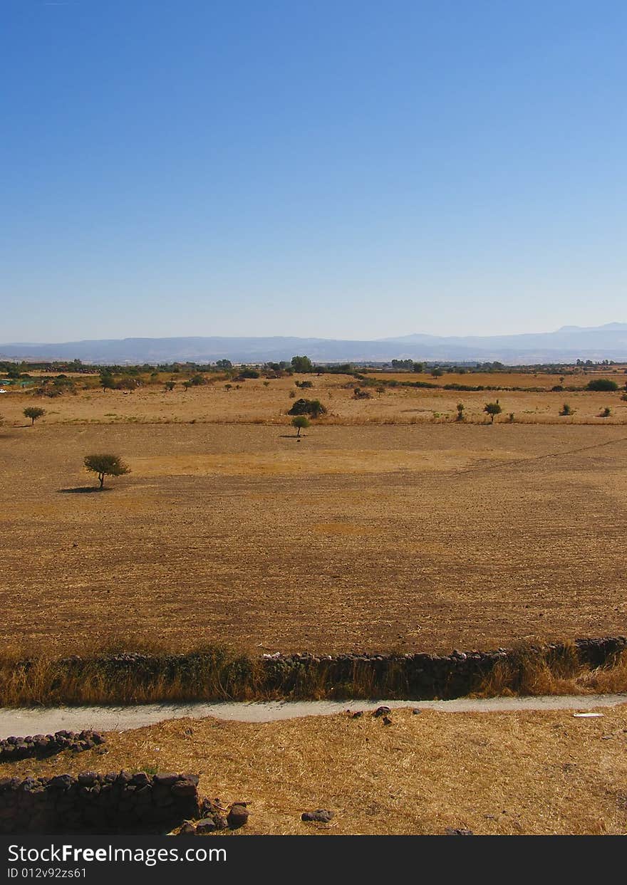 Plain with beautiful ground colors and hills on the horizon, clear blue sky *with space for text (copyspace)