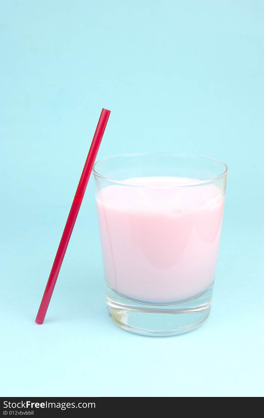 A strawberry flavoured glass of milk isolated against a blue background. A strawberry flavoured glass of milk isolated against a blue background