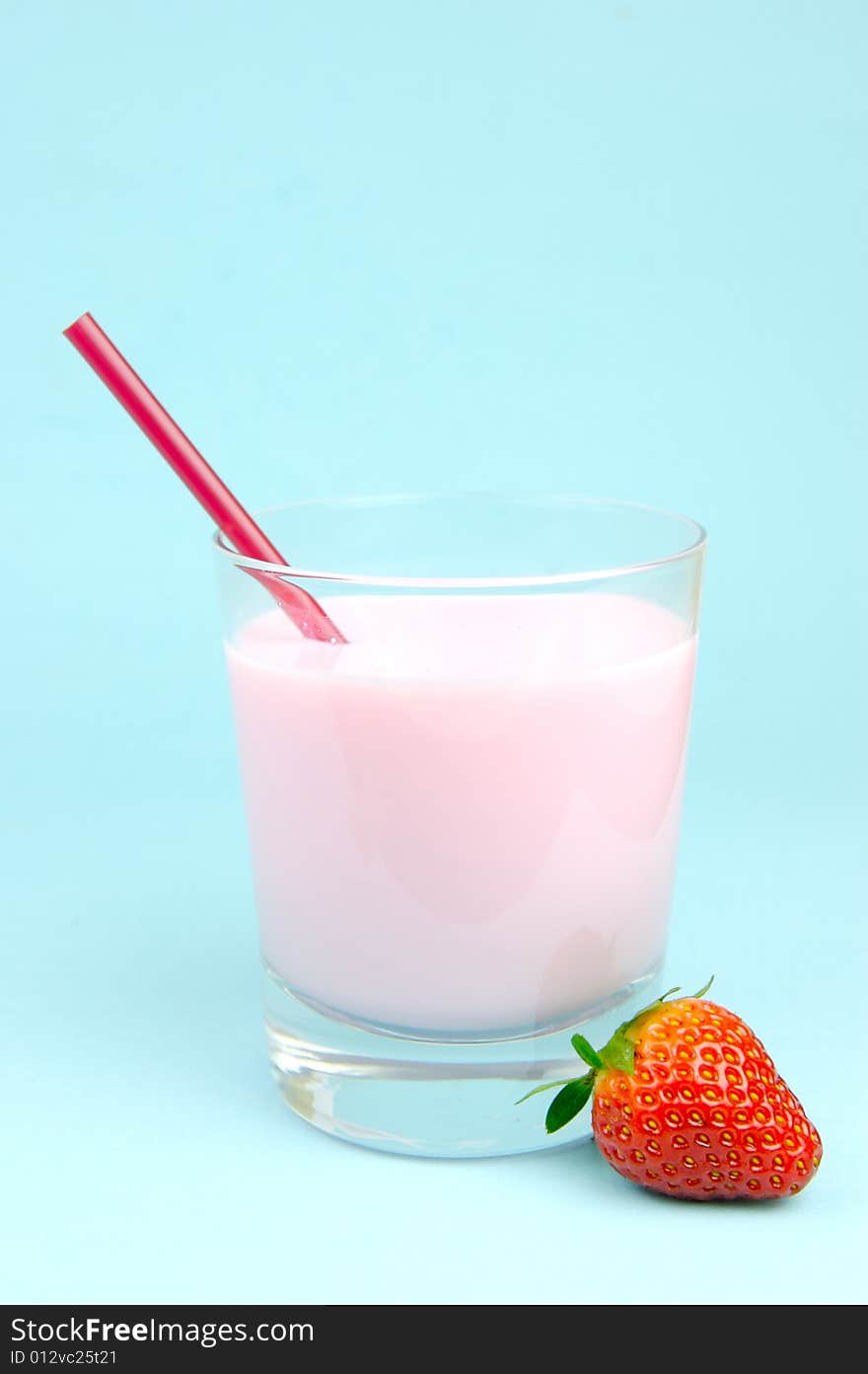 A strawberry flavoured glass of milk isolated against a blue background. A strawberry flavoured glass of milk isolated against a blue background