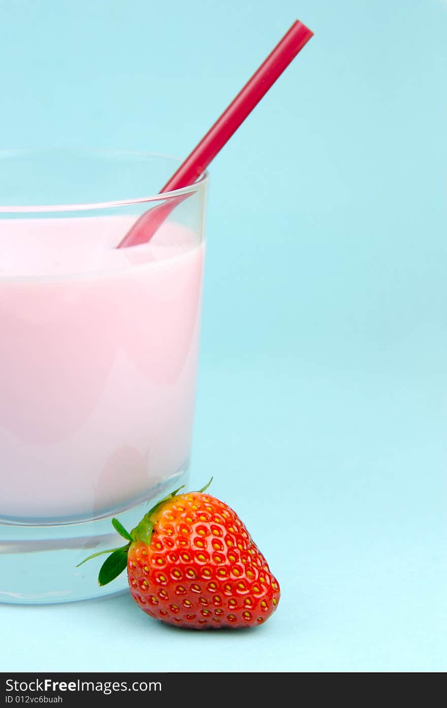 A strawberry flavoured glass of milk isolated against a blue background. A strawberry flavoured glass of milk isolated against a blue background