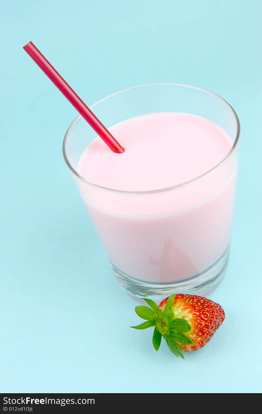 A strawberry flavoured glass of milk isolated against a blue background. A strawberry flavoured glass of milk isolated against a blue background