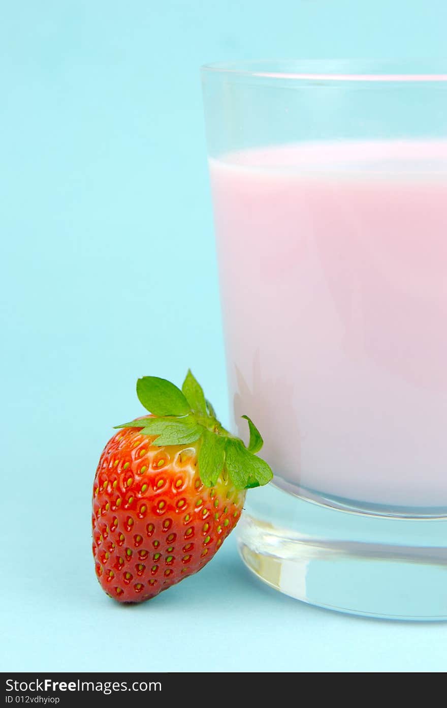 A strawberry flavoured glass of milk isolated against a blue background. A strawberry flavoured glass of milk isolated against a blue background