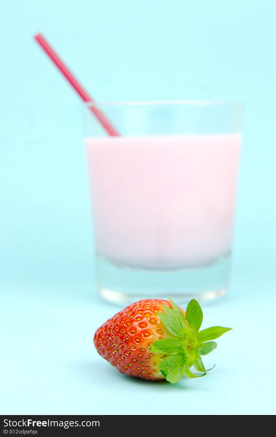 A strawberry flavoured glass of milk isolated against a blue background. A strawberry flavoured glass of milk isolated against a blue background