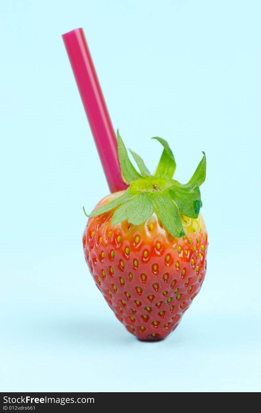 A strawberry with a straw isolated against a blue background. A strawberry with a straw isolated against a blue background