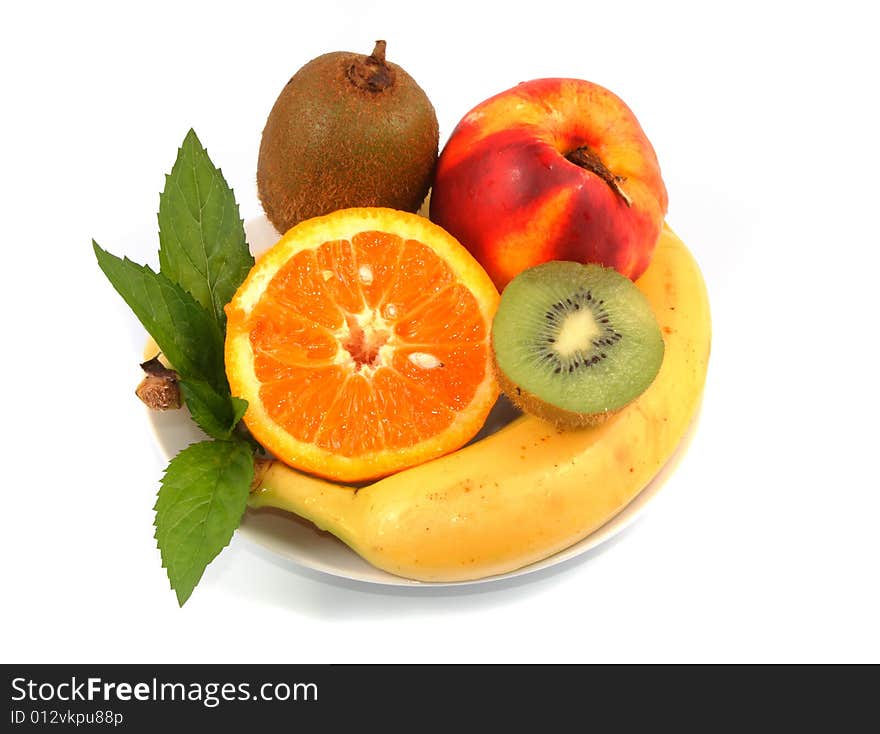 Orange, peach, banana and kiwi in a white plate on light background. Orange, peach, banana and kiwi in a white plate on light background.