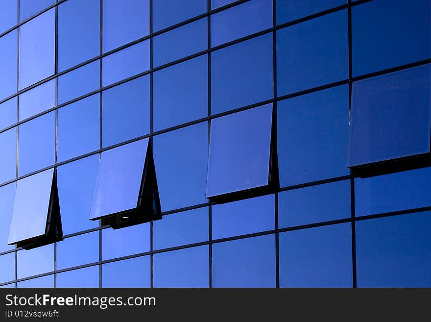 Open windows on blue glass wall of a modern building. Open windows on blue glass wall of a modern building