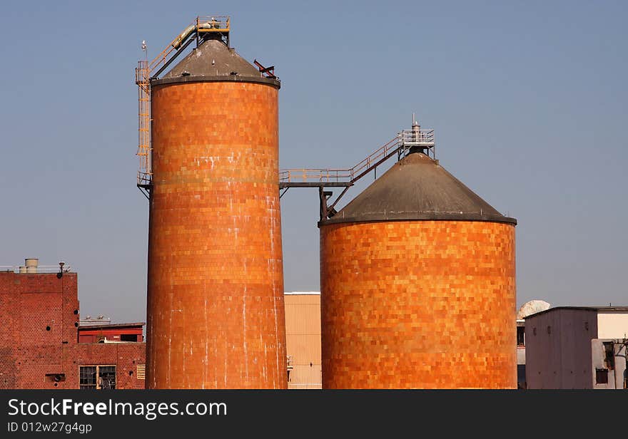 Two brick silos from a pulp mill with blue sky background.