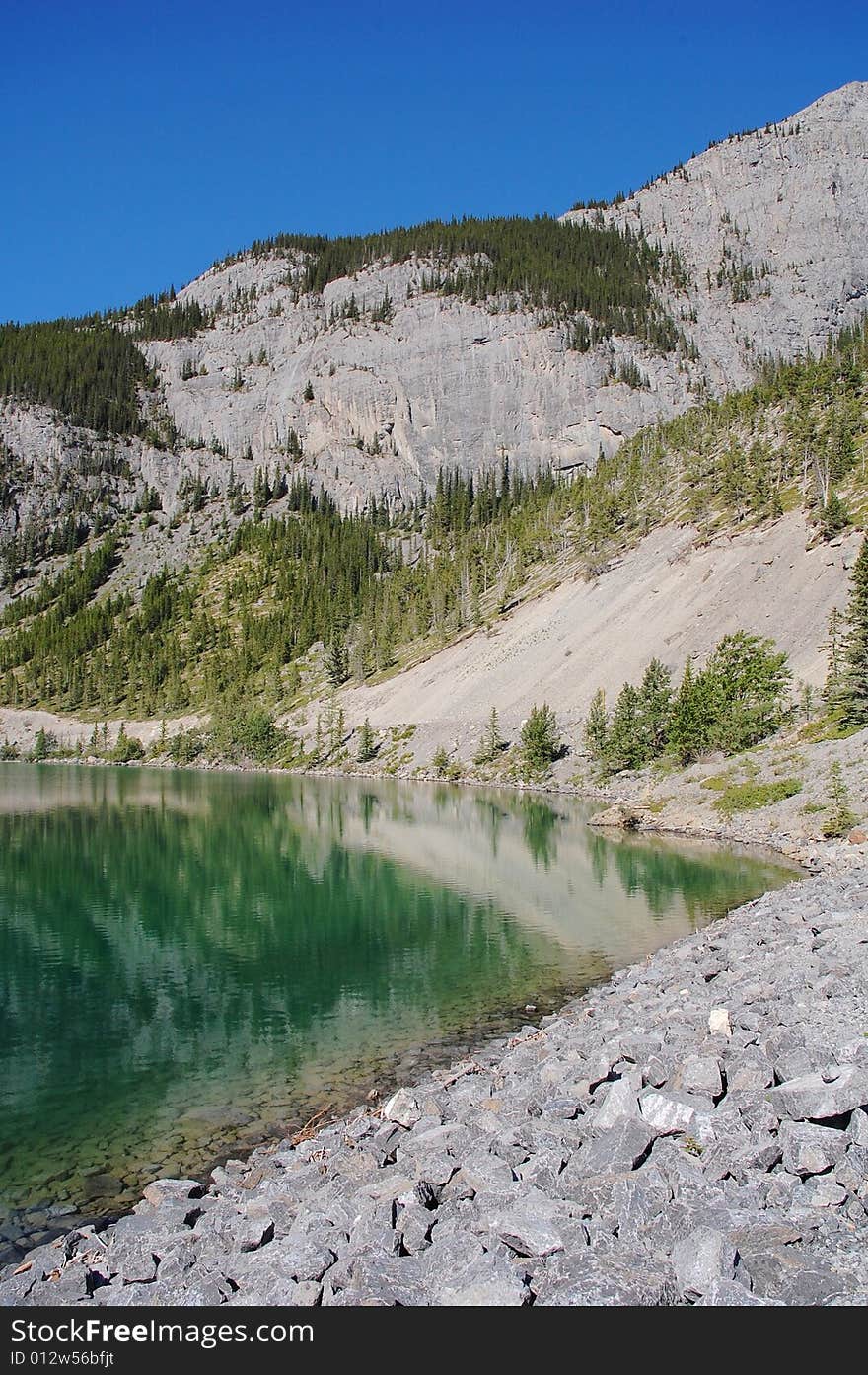 Alpine lake on mountains indefatigable, kananaskis country, alberta, canada