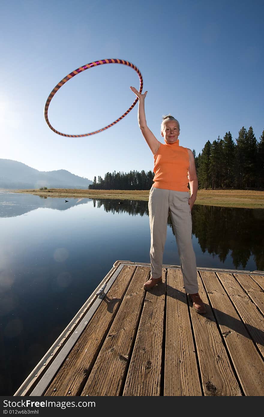 Senior woman hula hooping on lake boat ramp. Senior woman hula hooping on lake boat ramp