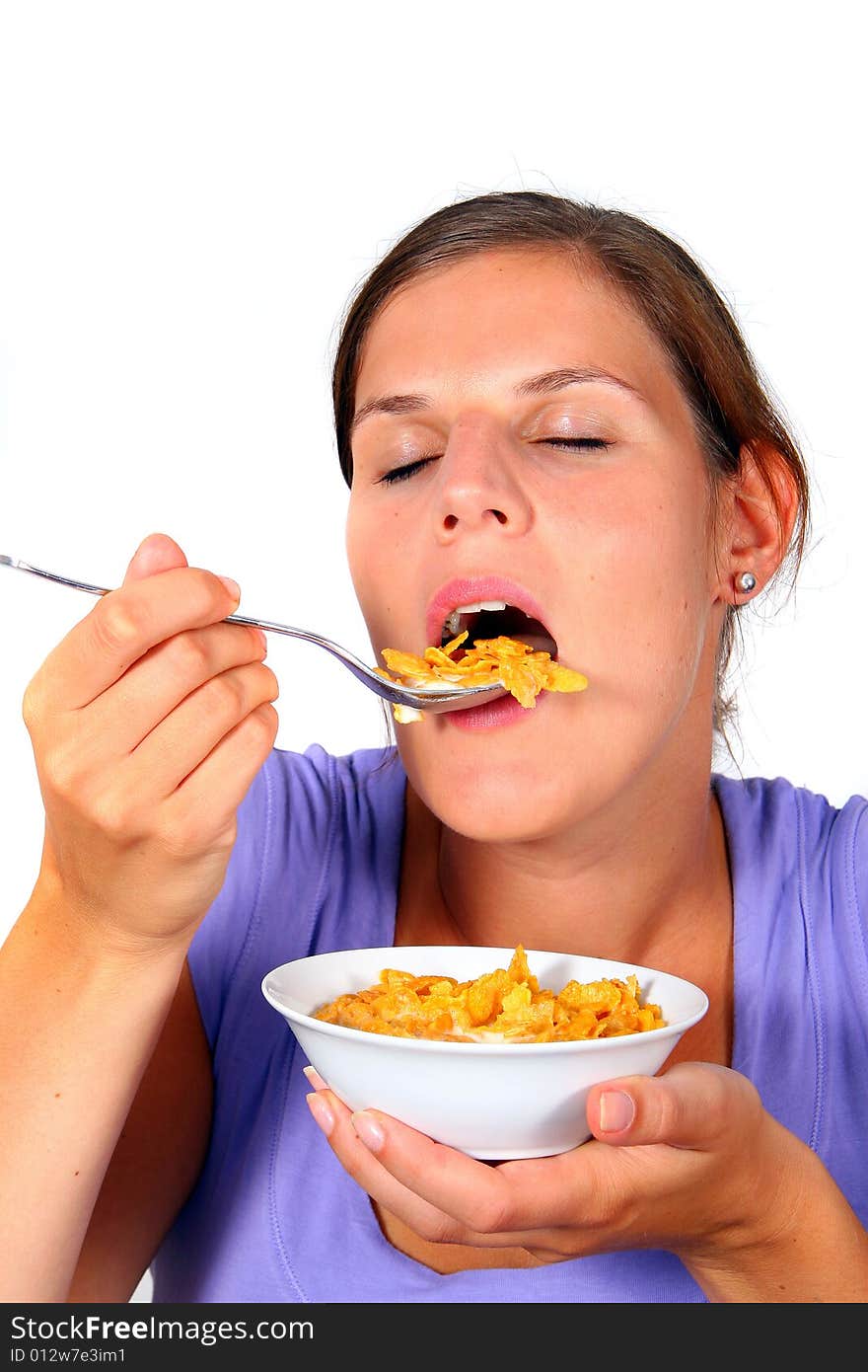 A young woman enjoys her crunchy cornflakes. Isolated over white. A young woman enjoys her crunchy cornflakes. Isolated over white.