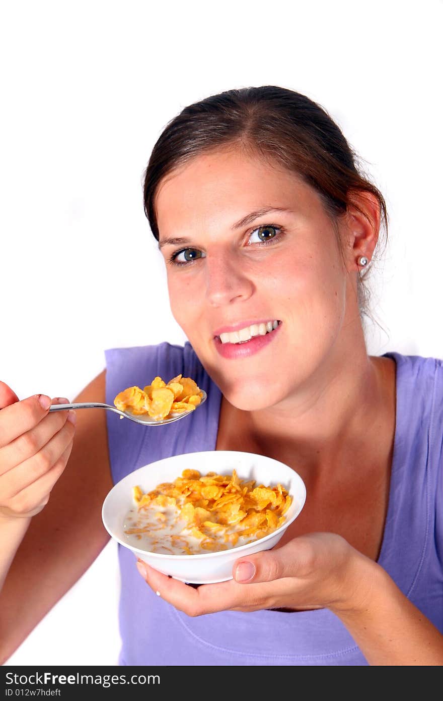 A young woman enjoys her crunchy cornflakes. Isolated over white. A young woman enjoys her crunchy cornflakes. Isolated over white.