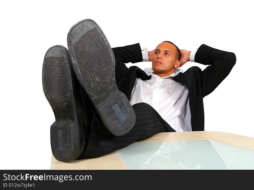 A young satisfied businessman sitting by desk at office feet on table thinking. A young satisfied businessman sitting by desk at office feet on table thinking.