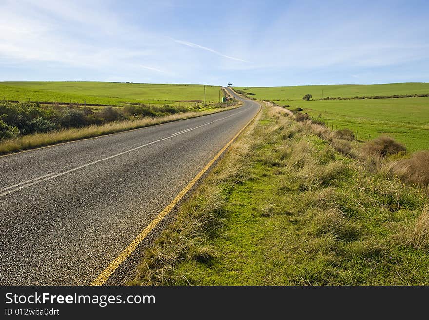 Deserted country-road running through green fields