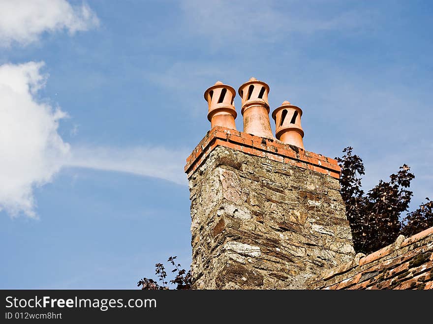 A trio of classic French chimney pots against a summer sky