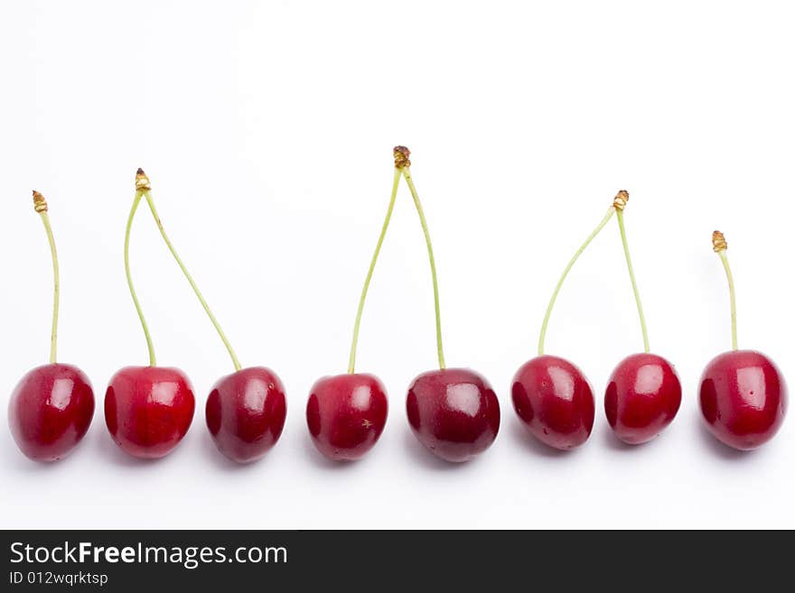 Row of red cherries on white background