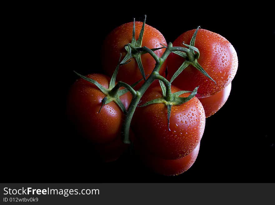 Tomatos on a mirror on black background