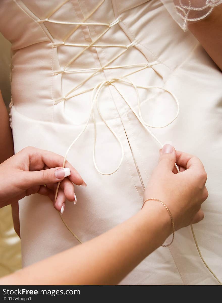 Young woman tightening the courset of a bride. Young woman tightening the courset of a bride