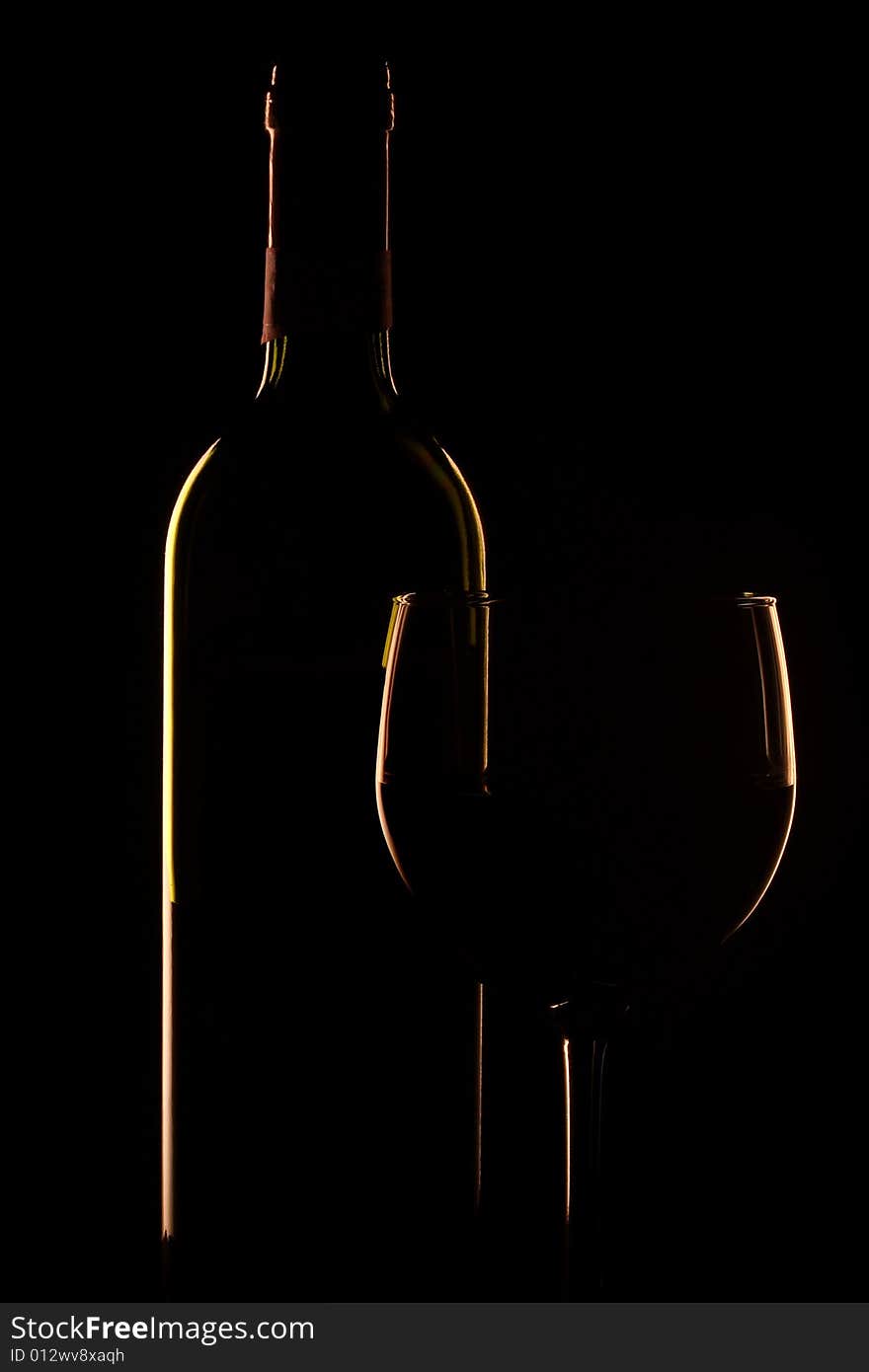 Bottle of wine and glass set against a black backdrop. Bottle of wine and glass set against a black backdrop