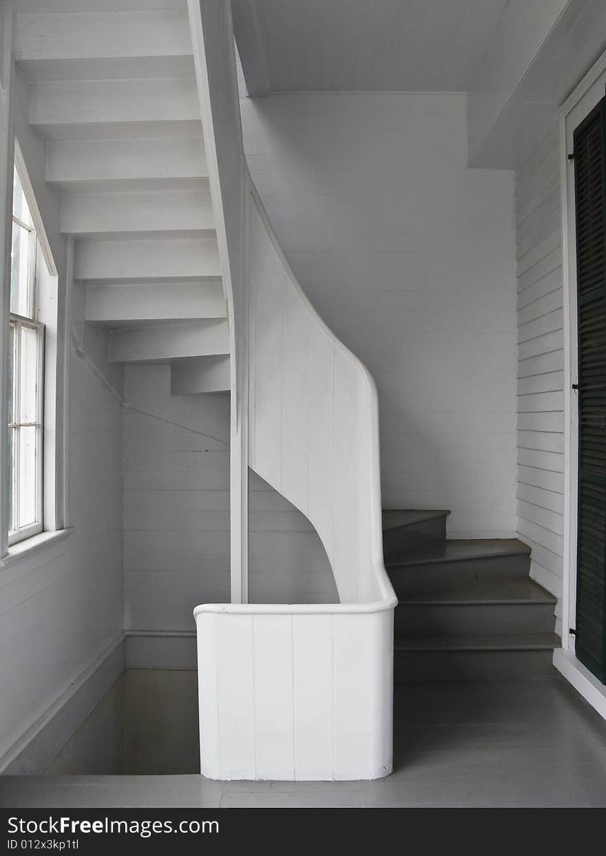 White wooden spiral stairs winds from one floor to another through the back porch. White wooden spiral stairs winds from one floor to another through the back porch.