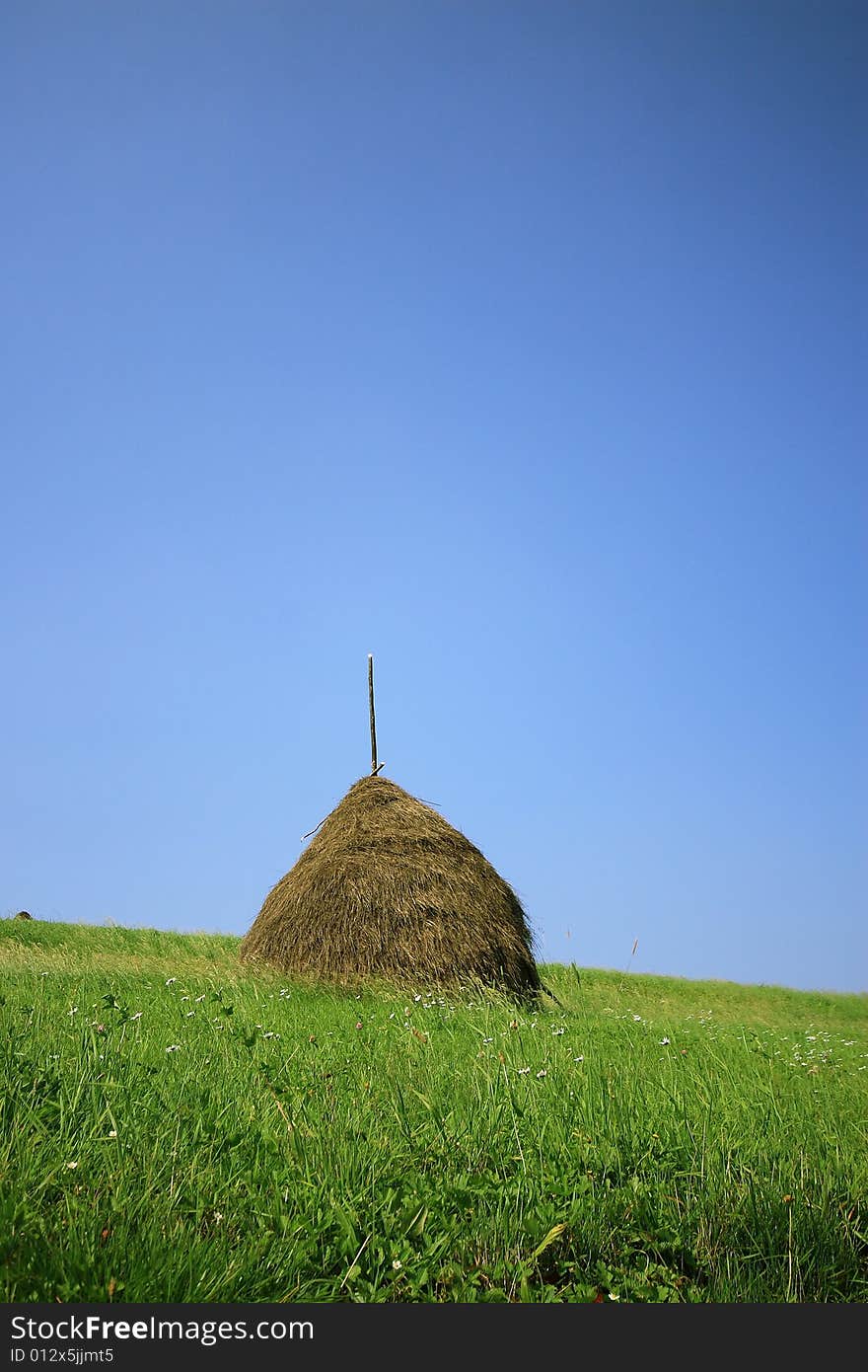 Haystack on a background of the blue sky and green grass