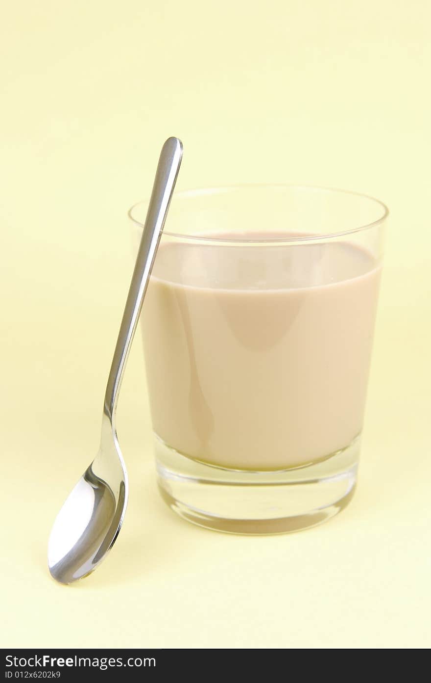 A glass of chocolate milk isolated against a yellow background