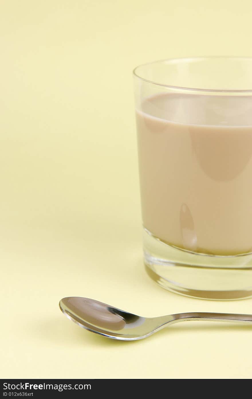 A glass of chocolate milk isolated against a yellow background