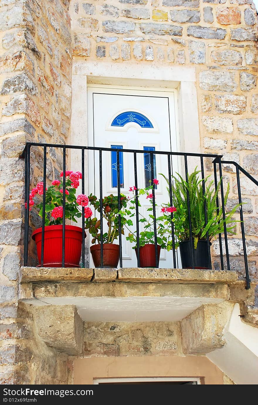 Entrance door of old stone house with flowerpots in Budva. Entrance door of old stone house with flowerpots in Budva