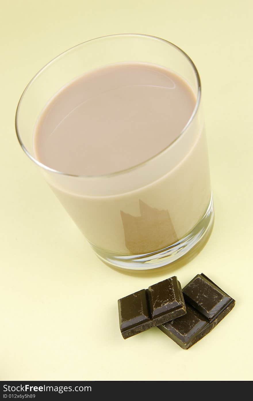 A glass of chocolate milk isolated against a yellow background