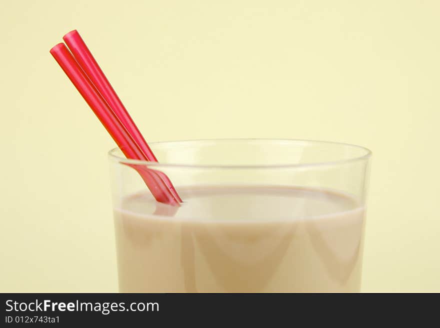 A glass of chocolate milk isolated against a yellow background