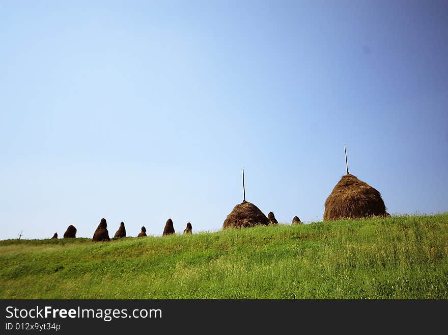 Haystacks on a background of the blue sky and green grass