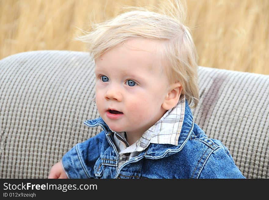 A small child on a old chair in the middle of a field. A small child on a old chair in the middle of a field