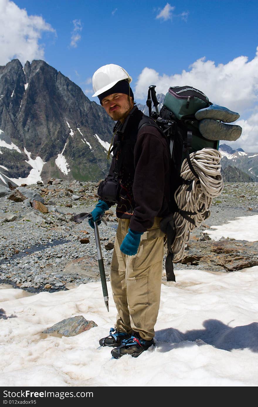 Climber in crampon and helmet standing on snow in mountains. Climber in crampon and helmet standing on snow in mountains